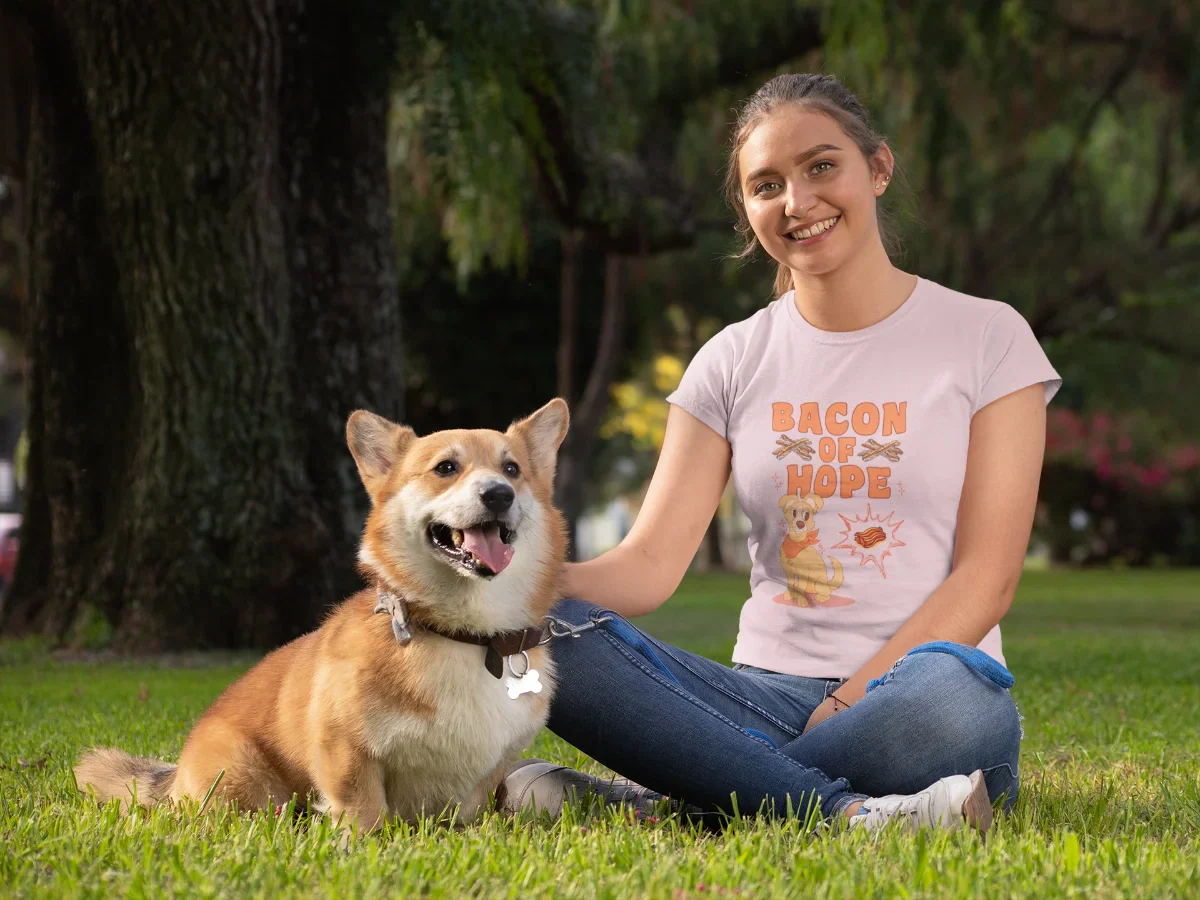 Comic-Hund mit Halstuch schaut hoffnungsvoll auf ein schwebendes Stück Bacon – darüber der Schriftzug „Bacon of Hope“, eingerahmt von Speck-Streifen und Glitzerelementen. Humorvolles Design für Hundeliebhaber.
