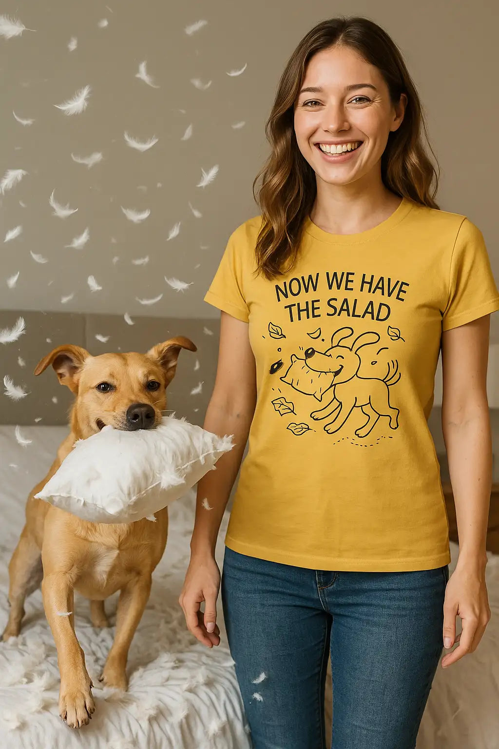 Frau Ende 20 steht lächelnd im chaotischen Schlafzimmer, während ihr Hund mit einem zerbissenen Kissen im Maul Federn durchs Zimmer wirbelt. Sie trägt ein gelbes T-Shirt mit dem Spruch „Now we have the salad“ und einem gezeichneten Hundemotiv.